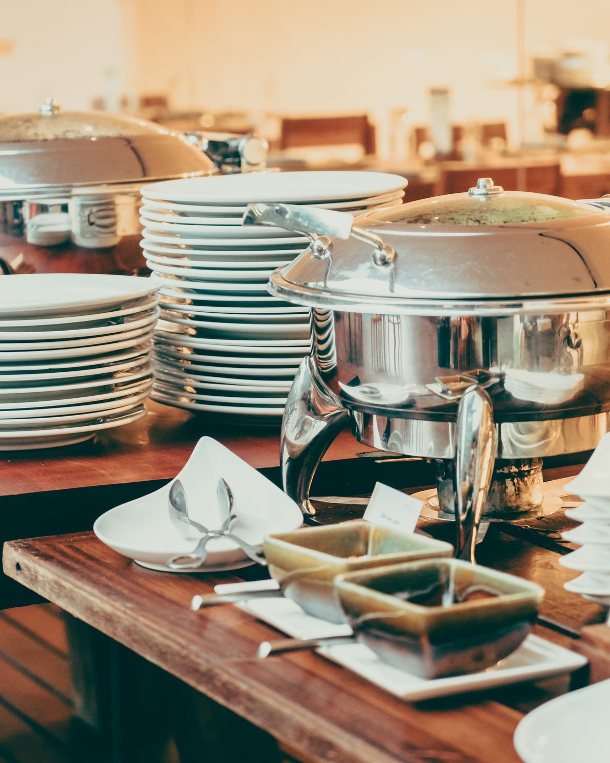 Catering buffet with chafing dishes and stacked plates